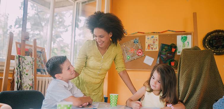 Teacher standing at kids desks.